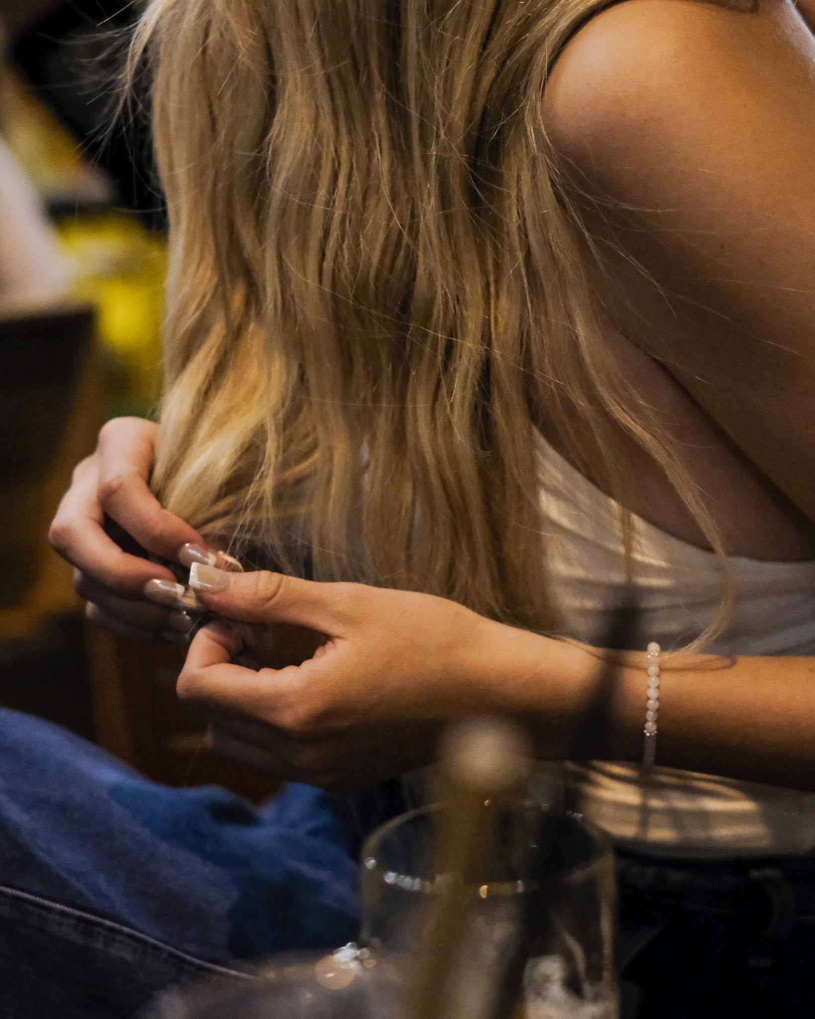 Woman with long blonde hair sitting at a bar, wearing a handcrafted moonstone and silver bracelet - minimalist jewelry by elswre