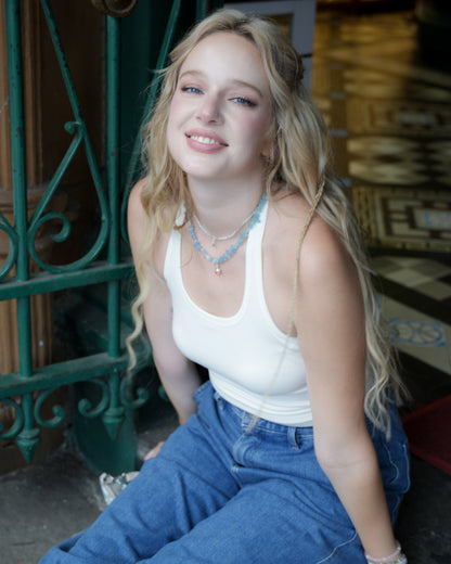 Model wearing aquamarine necklace with pearl and citrine charm, styled with a white tank top and jeans – modern gemstone jewelry by elswre