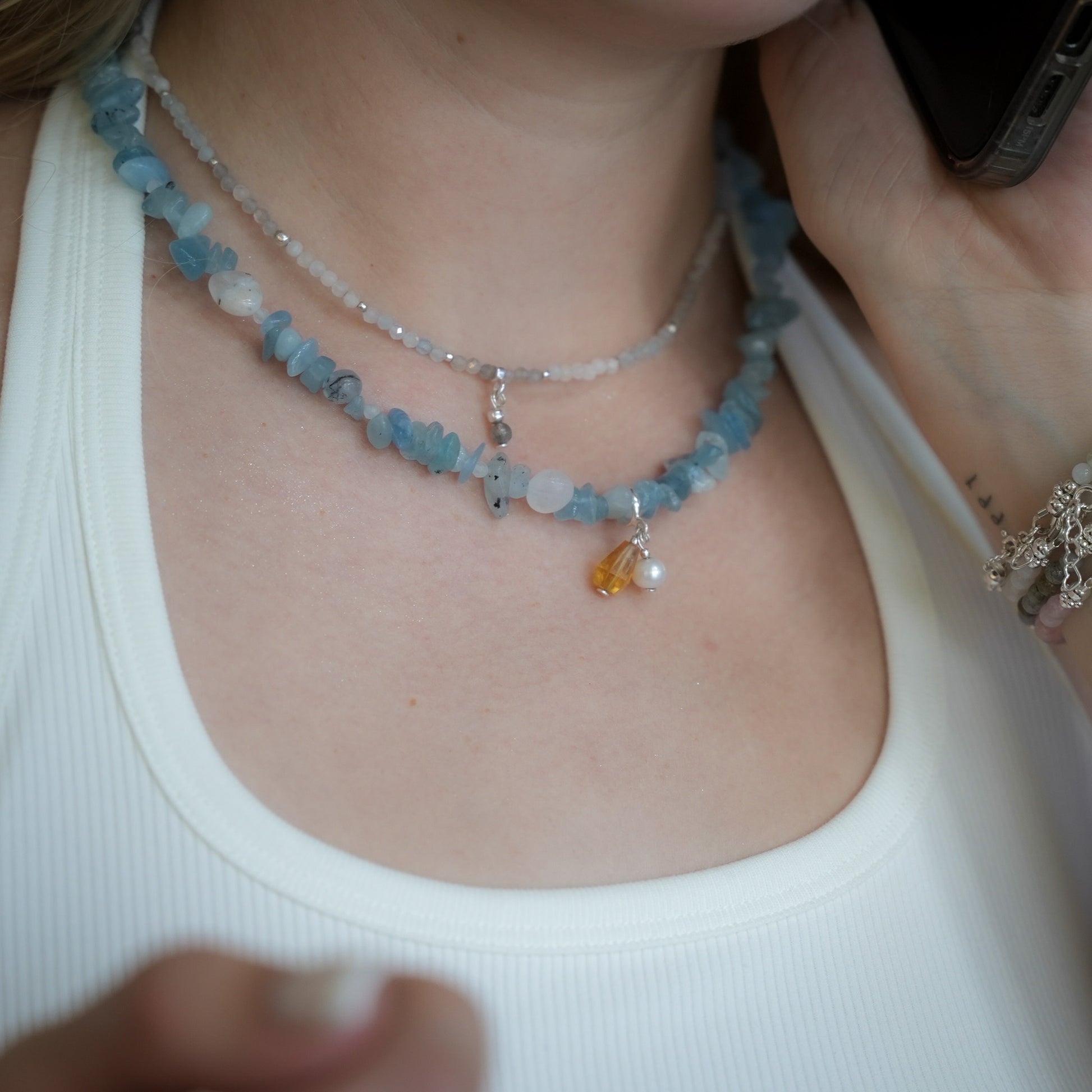 Close-up of aquamarine necklace with pearl and citrine charm, worn with a white ribbed tank top – handmade gemstone jewelry by elswre