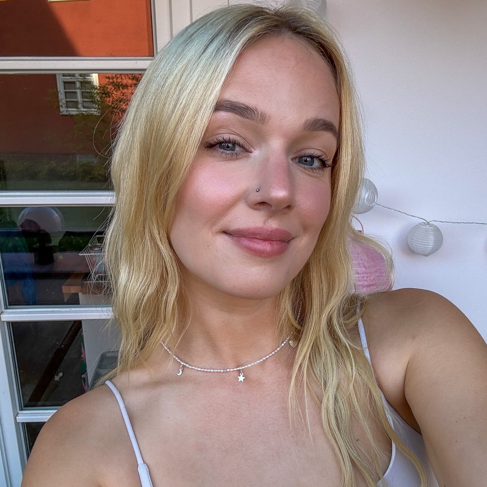 Model wearing the Hoi An Necklace with silver moon, star, and heart charms on pearl strand - handmade by elswre jewelry