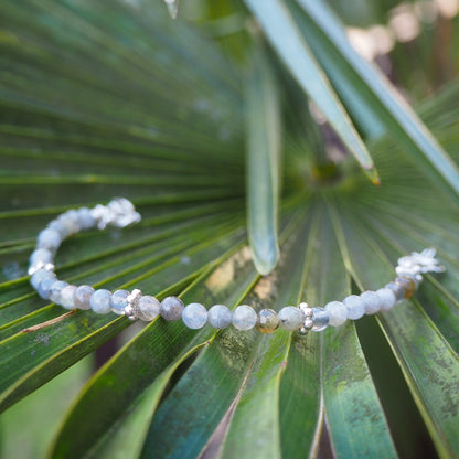 Handcrafted labradorite and silver bracelet placed on green palm leaves – natural light product photo for elswre’s travel-inspired jewelry collection
