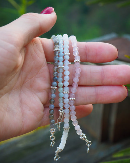 Hand holding three handcrafted gemstone bracelets made from aquamarine, moonstone, rose quartz, and labradorite with silver details - minimalist jewelry by elswre