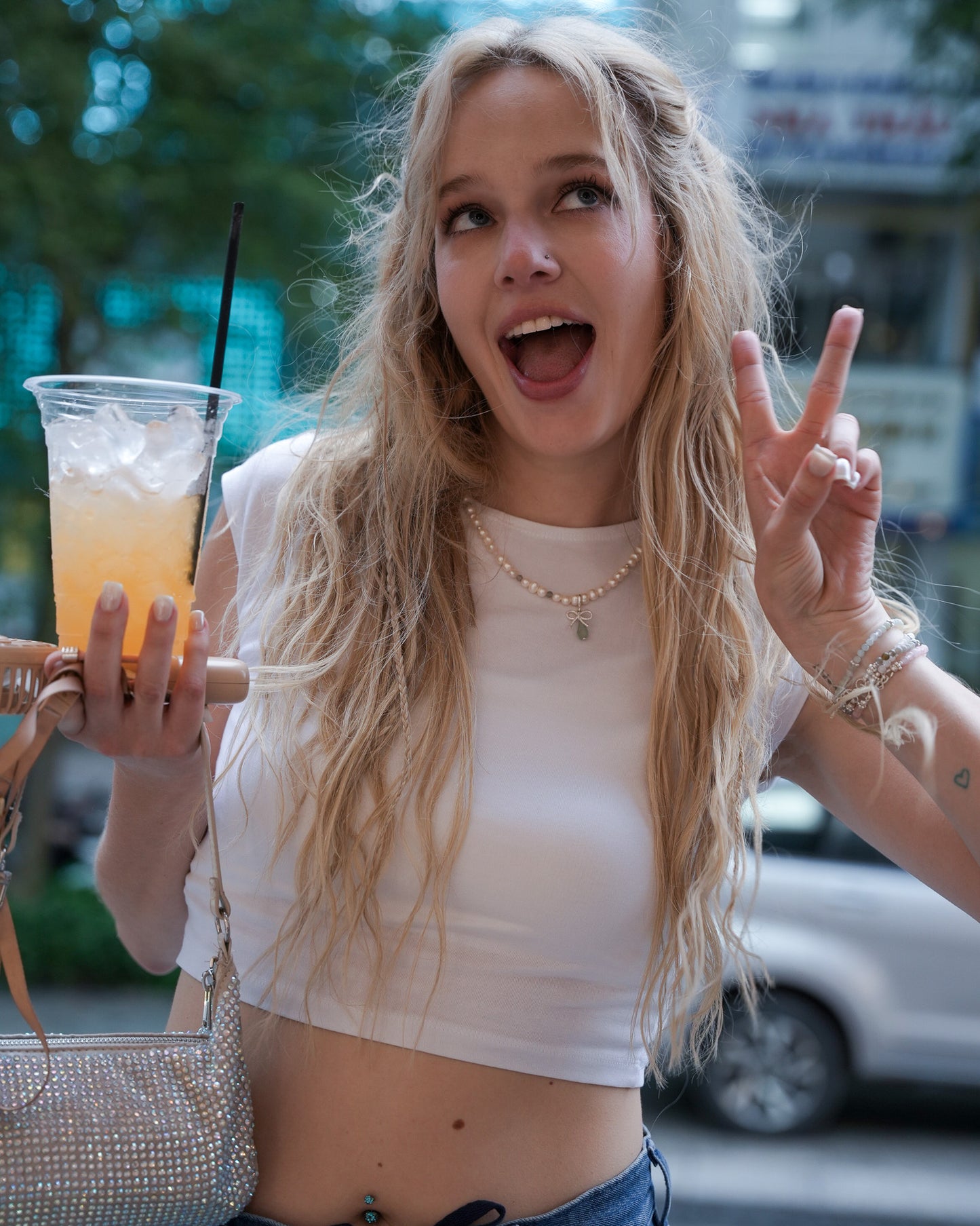 Model wearing pearl necklace with aquamarine and silver bow charms, photographed outdoors – playful and elegant jewelry from elswre.