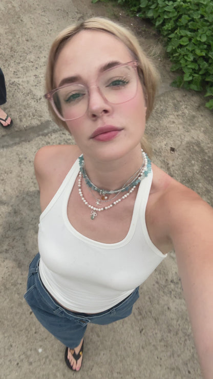 Short video of a pearl necklace with aquamarine and silver bow charms gently moving in natural light – handmade gemstone jewelry by elswre.